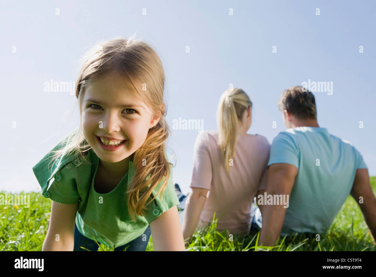 Deutschland, Bayern, München, Familie sitzt auf Wiese, Mädchen (6-7) im Vordergrund, Lächeln, Porträt Stockfoto