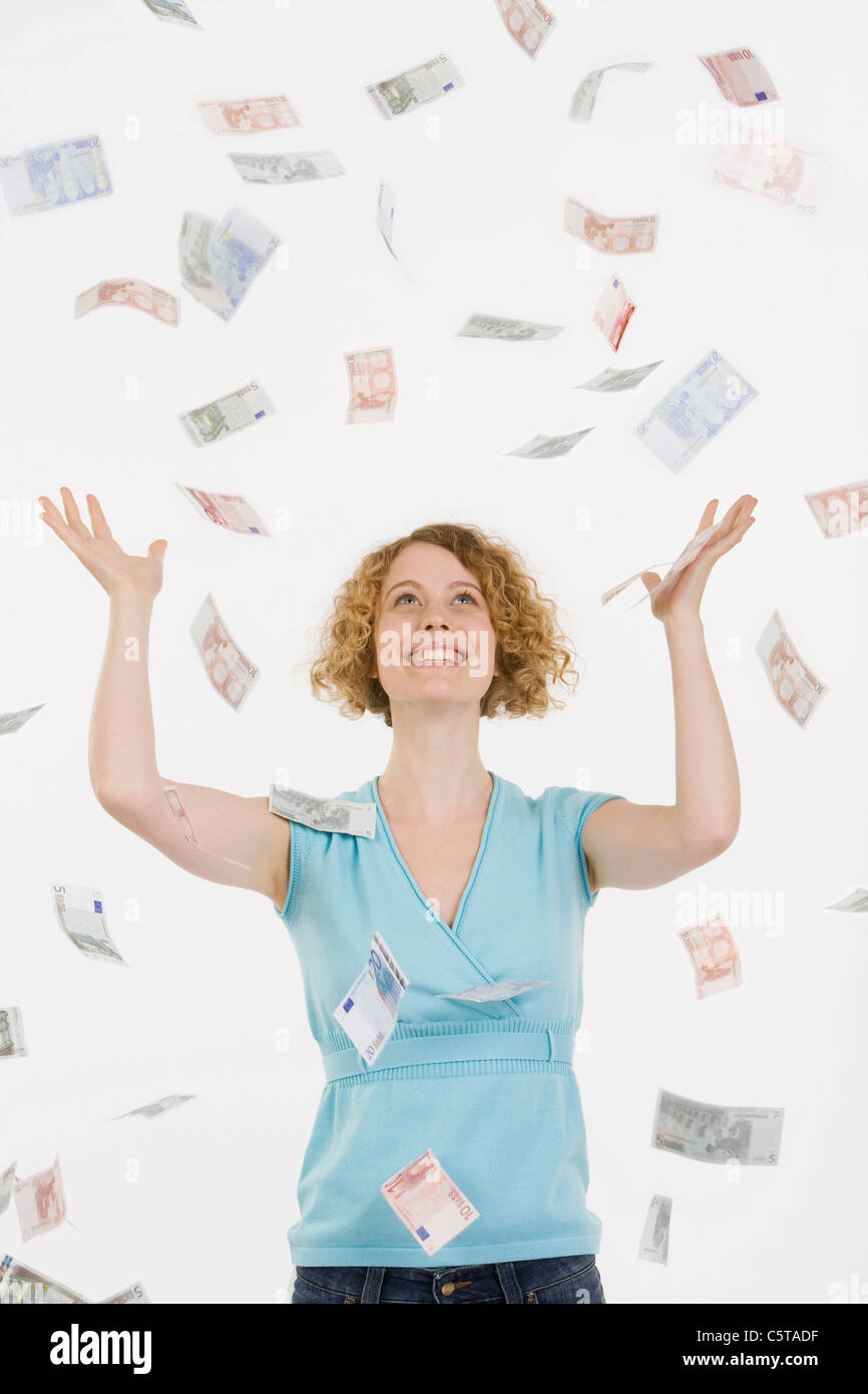 Junge Frau mit fallenden Euro-Banknoten, Lächeln, Porträt Stockfoto