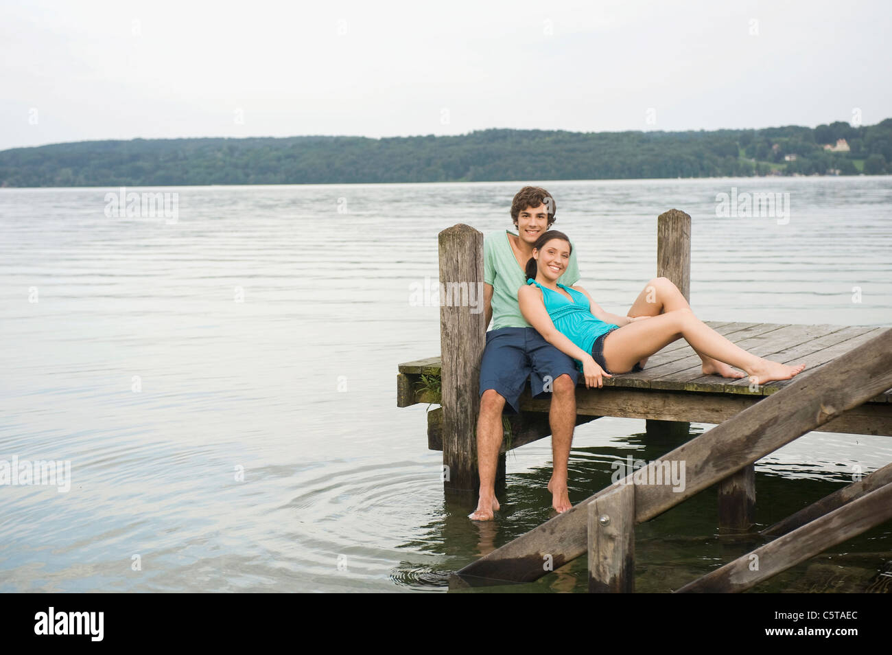 Deutschland, Bayern, Starnberger See, junges Paar sitzt am Steg Stockfoto