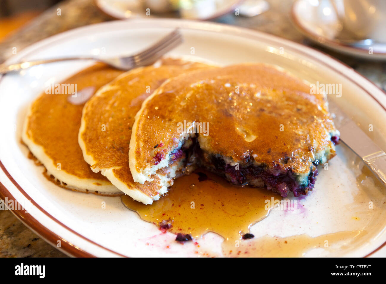 Heidelbeer-Pfannkuchen und Ahornsirup im Café in New York City Stockfoto