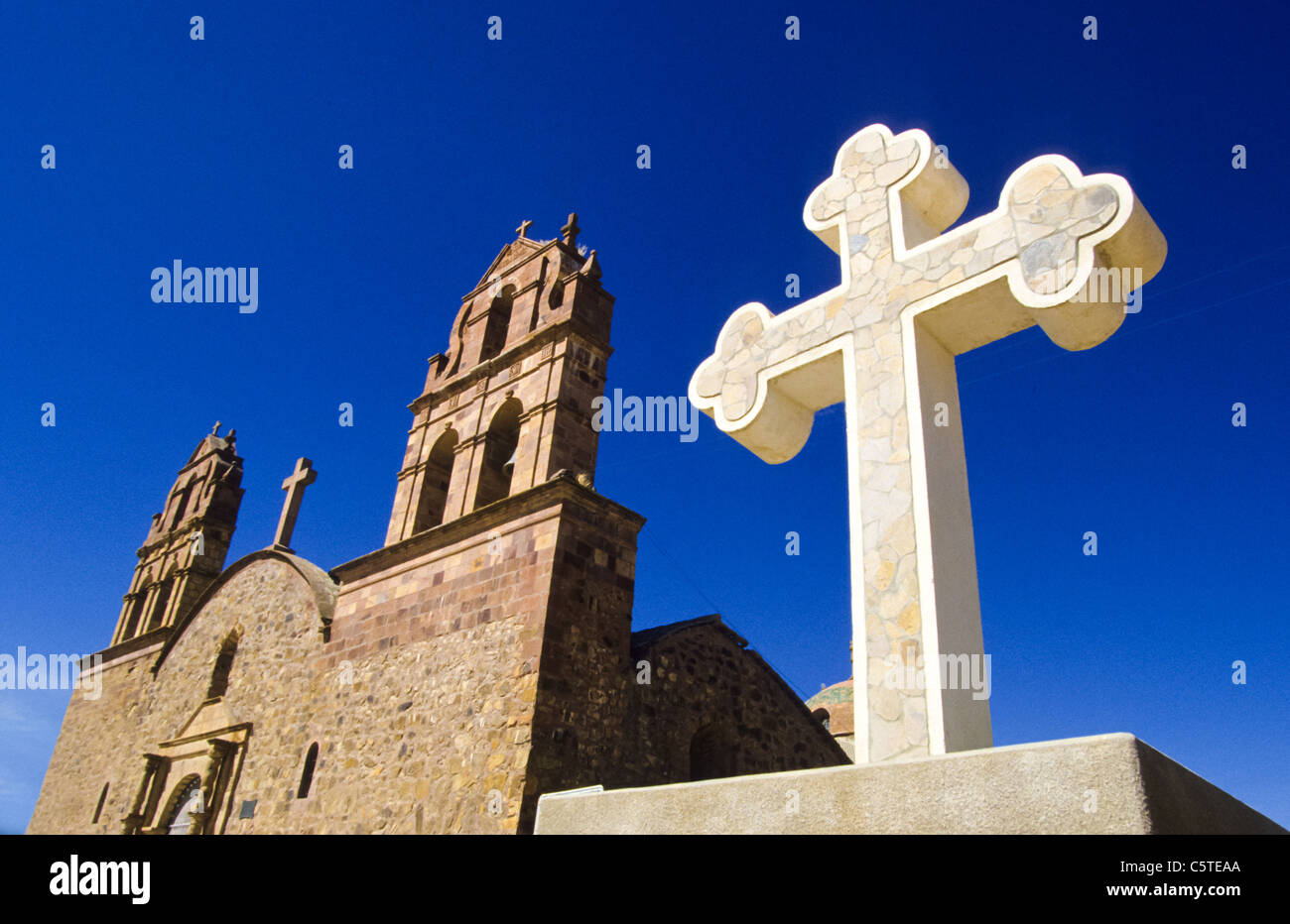 Bolivianische Kirche mit einem großen weißen Kreuz außerhalb, vor einem strahlend blauen Himmel Stockfoto