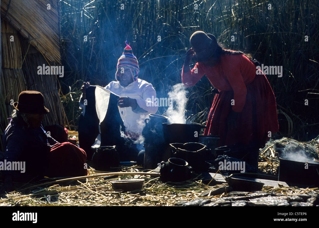 Uros Indianer rund um das Rauchen outdoor-Küche auf Papyros im Titicaca-See Stockfoto