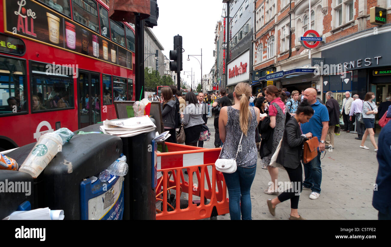 Käufer inmitten Mülltonnen warten auf roten Bus auf geschäftige Oxford Street in der Nähe von Baustellen an der Bond St. U-Bahn-Station in London UK KATHY DEWITT Stockfoto