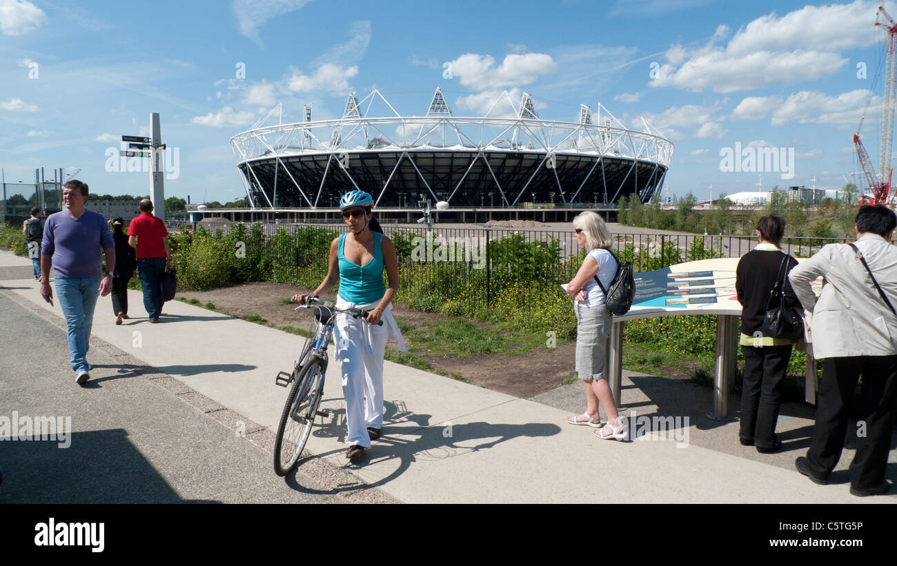 Junge Frau mit Fahrrad und Helm auf Greenway in der Nähe des Ansicht-Tube mit anderen Besuchern 2012 Olympic Stadium in London England Stockfoto