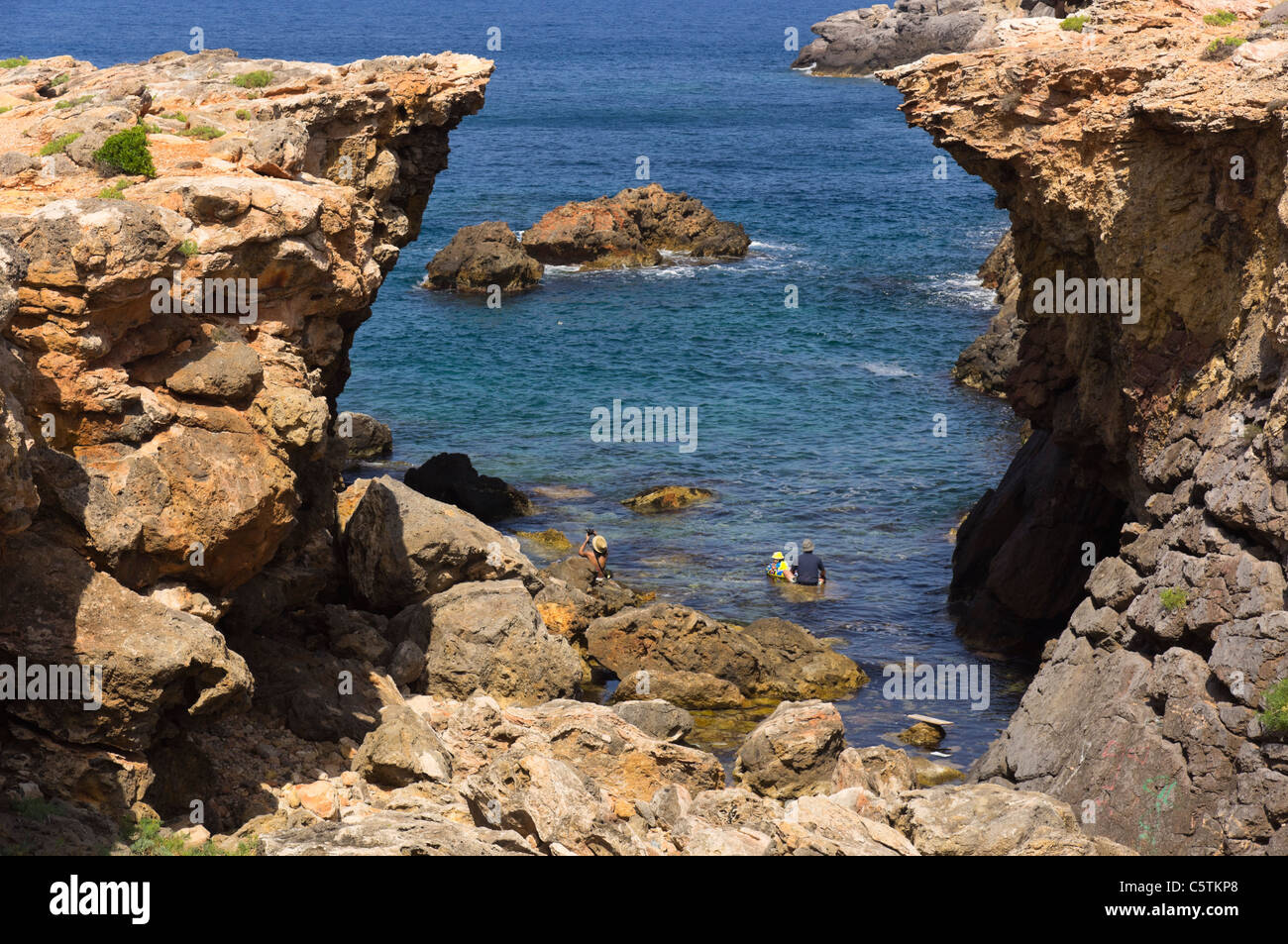 Ibiza, Balearen, Spanien - die felsige Bucht und die Bucht von Es Pou des Lleó. Junge Familie im "Löwenmaul" schwimmen. Stockfoto