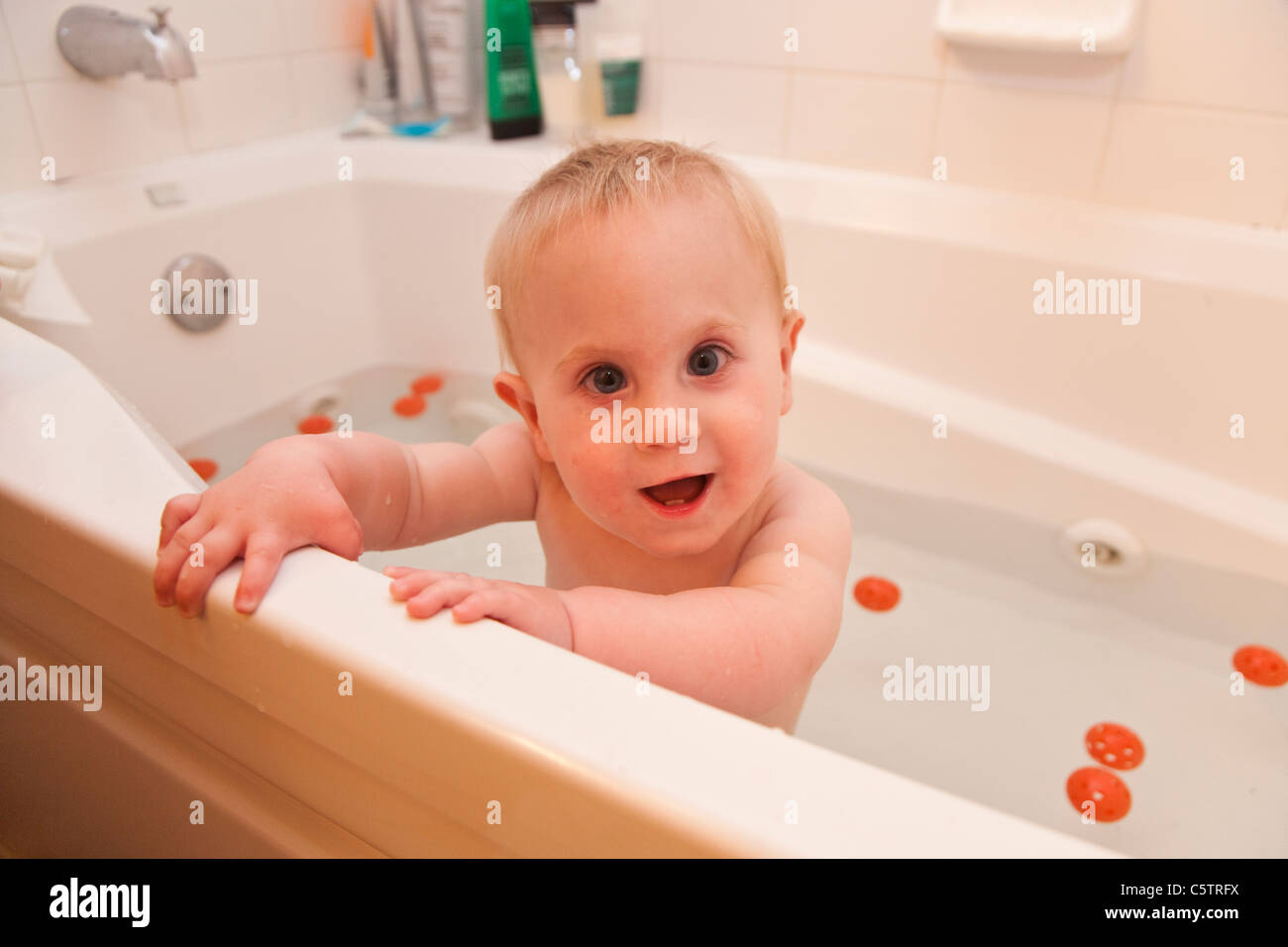 Ein kleines, fair haired junge festhalten an der Seite des Bades und Ausschau, während Baden. Stockfoto