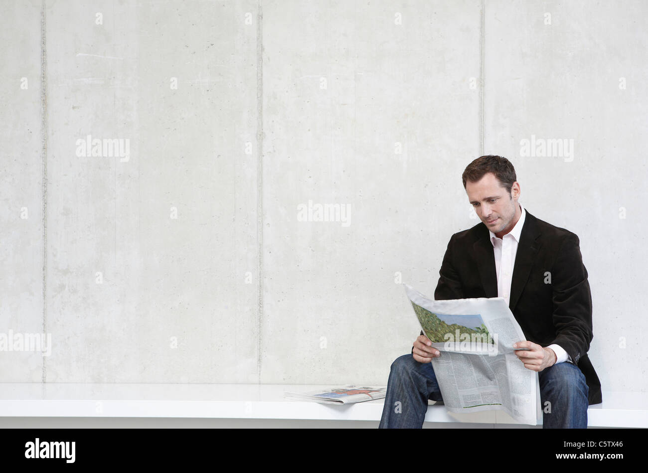 Deutschland, Köln, Geschäftsmann, sitzen auf der Bank und liest Zeitung, Porträt Stockfoto