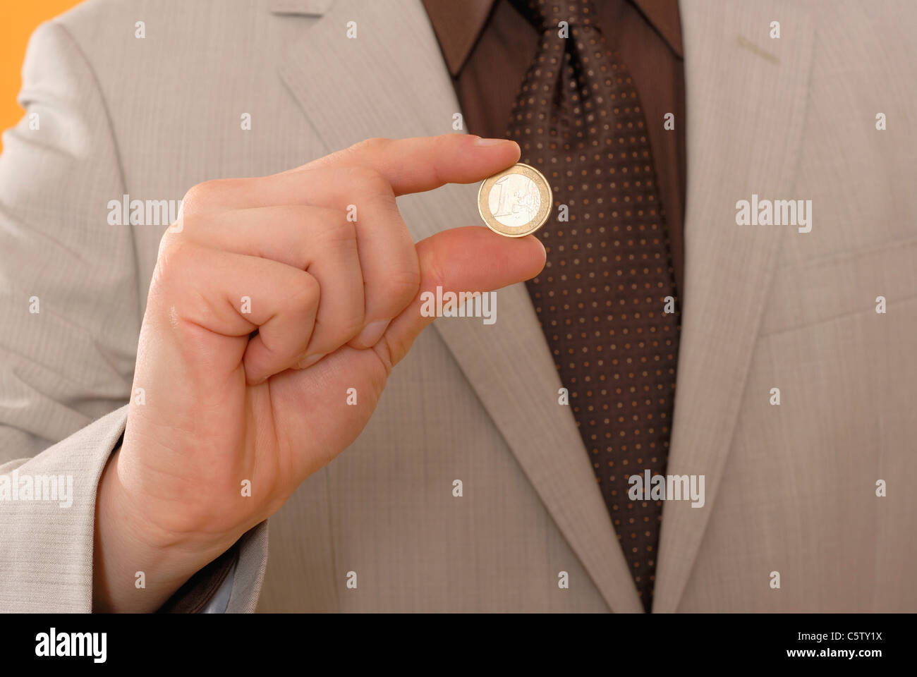 Mann hält Euro-Münze, Mittelteil, Nahaufnahme Stockfoto