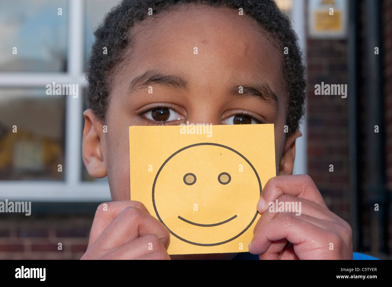 Junge Schuljunge hielt eine Smiley-Gesicht-Karte Stockfoto