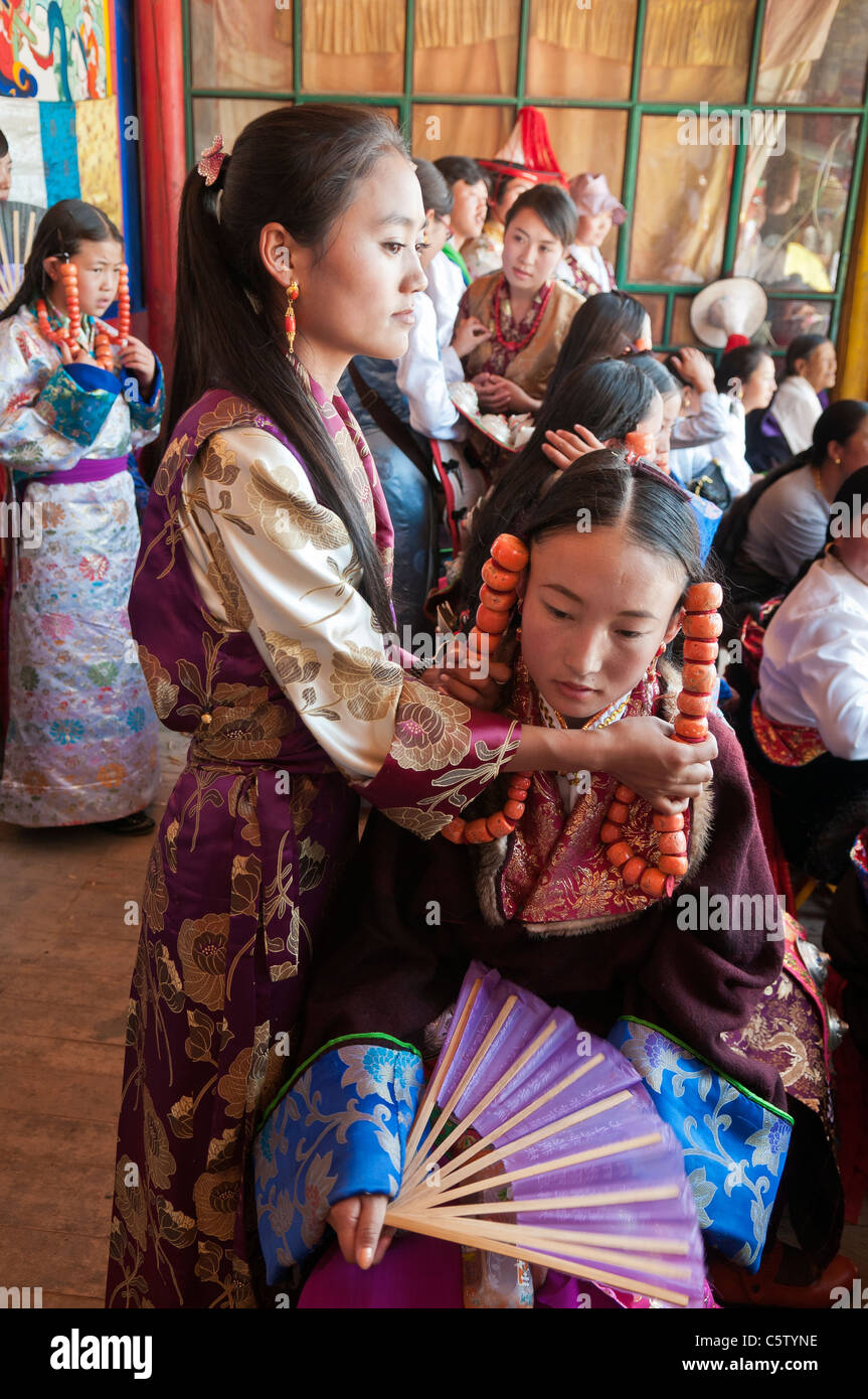 Junge Mädchen tragen von schweren Korallen Schmuck wartet auf Schamanen Erntefest, Tongren, Qinghai Provinz, China Stockfoto