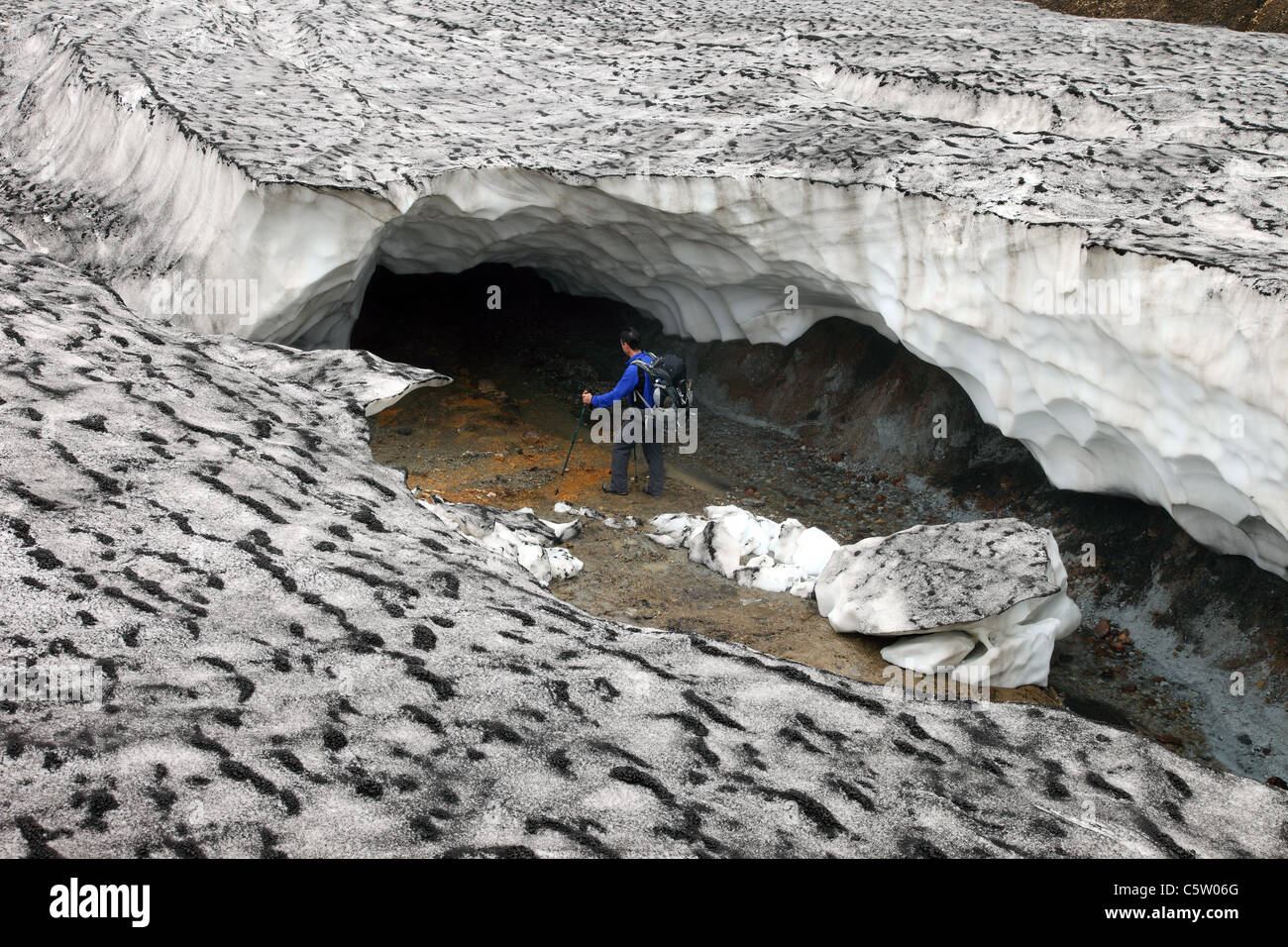 Wanderer auf der Suche in den Eingang der eingestürzten Eishöhle auf dem Laugavegur-Wanderweg Fjallabak Gebiet Islands Stockfoto