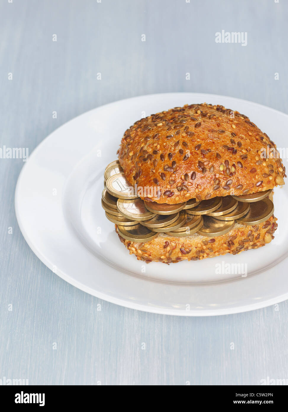 Brötchen mit 1-Euro-Münzen auf Platte Stockfoto