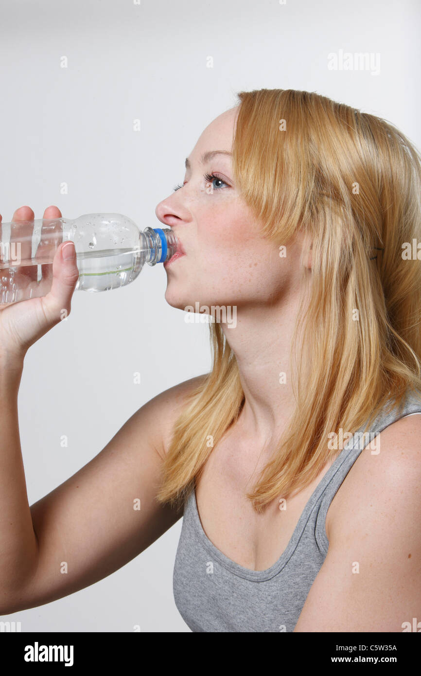 Junge Frau trinkt aus Wasserflasche, Porträt Stockfoto