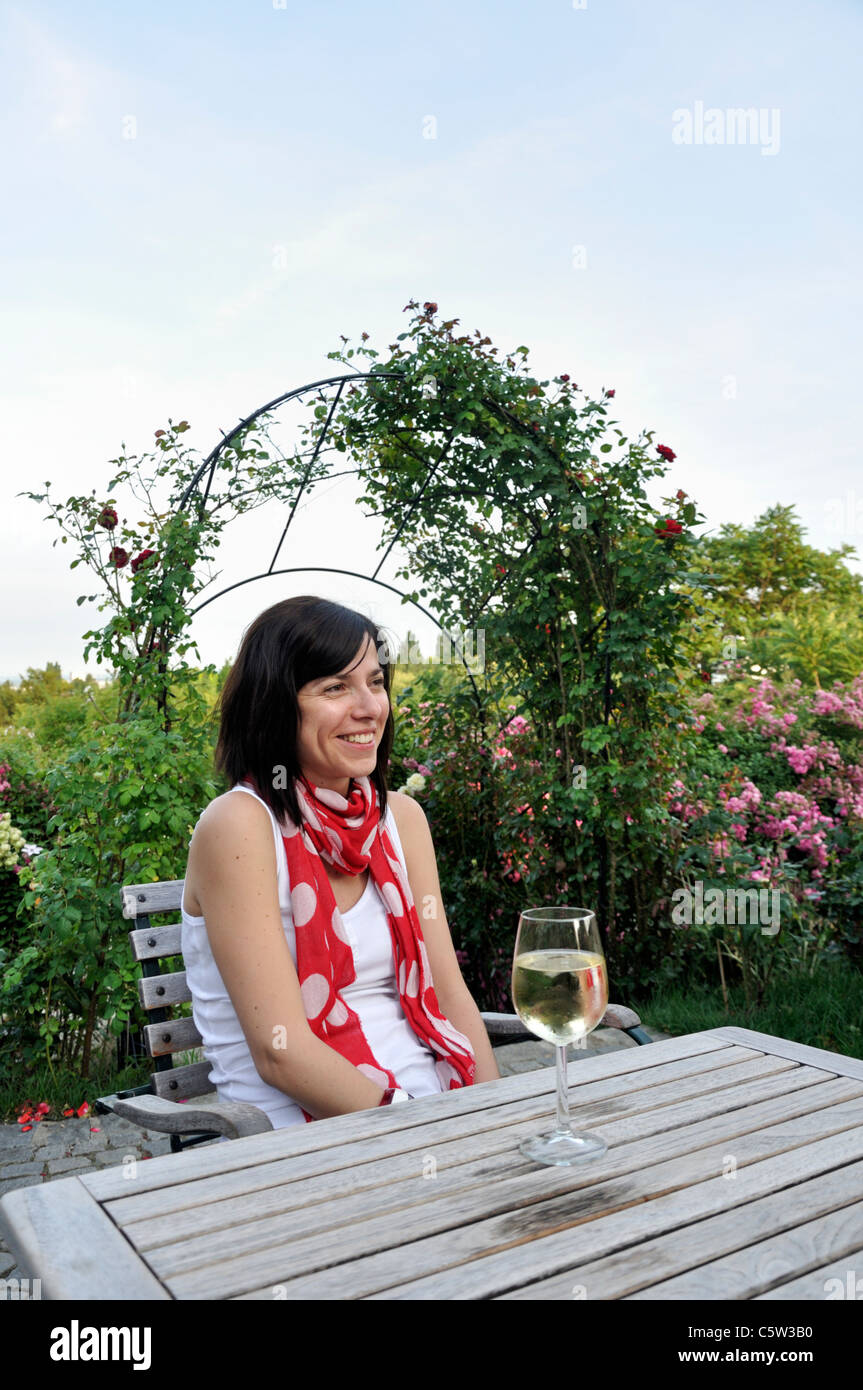 Junge Frau sitzt am Tisch mit Glas Weißwein Stockfoto