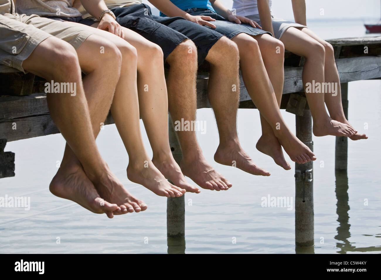 Deutschland, Bayern, fünf Personen sitzen am Steg, niedrige Abschnitt Stockfoto