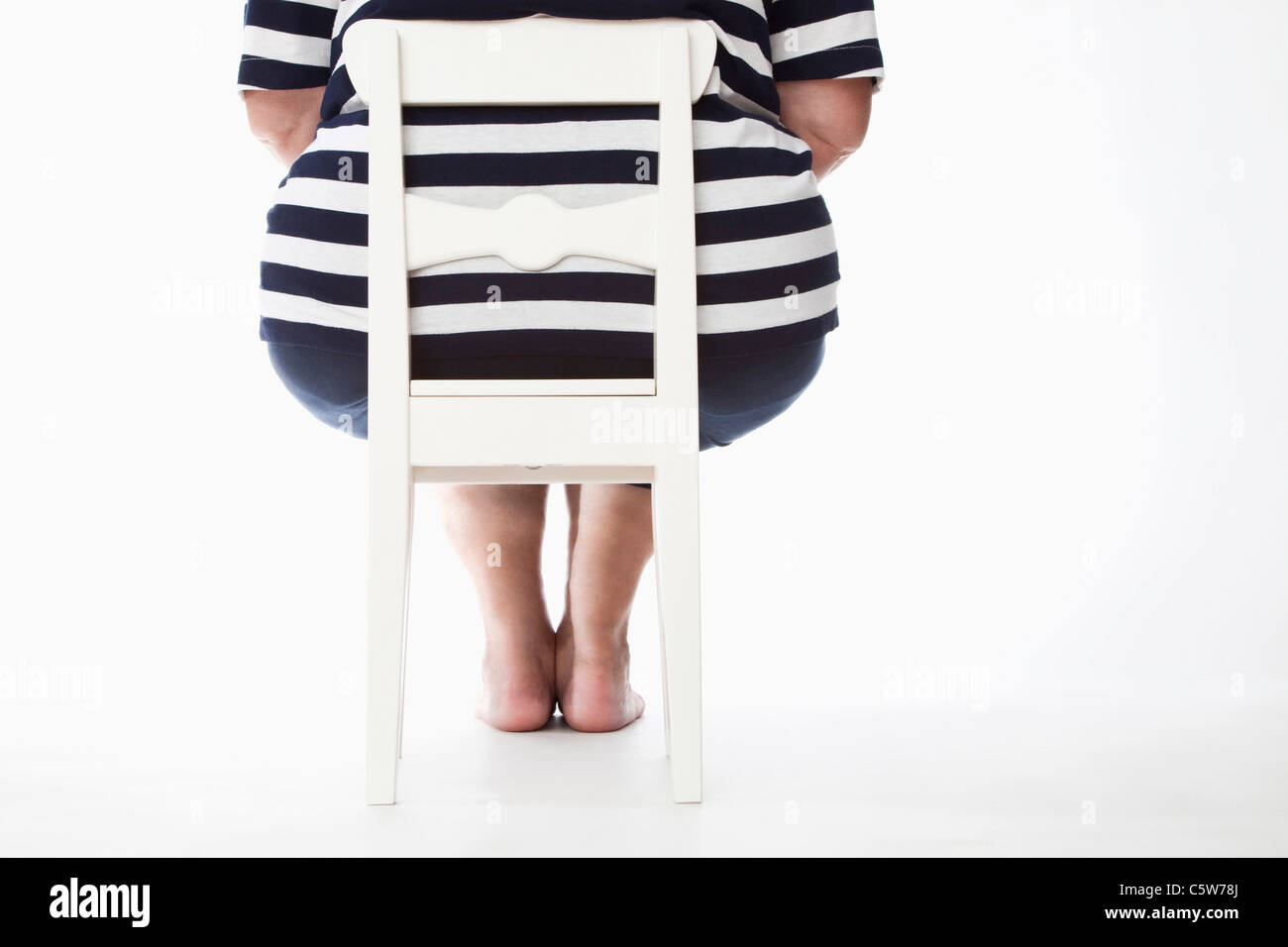 Übergewichtige Frau auf Stuhl, Rückansicht Stockfoto