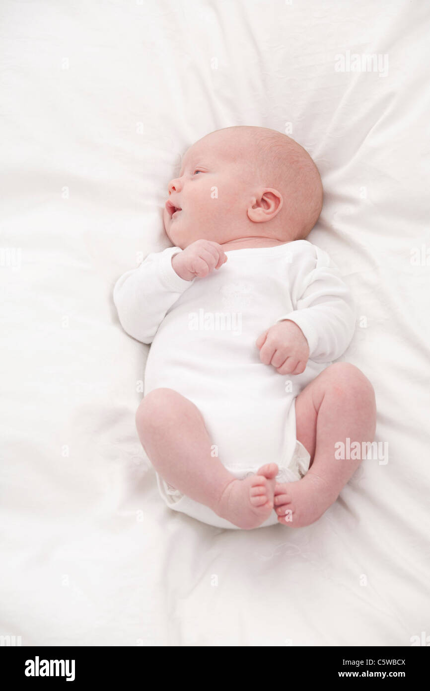 Deutschland, München, (0-1 Monate) Baby Boy auf Bett, wegschauen Stockfoto