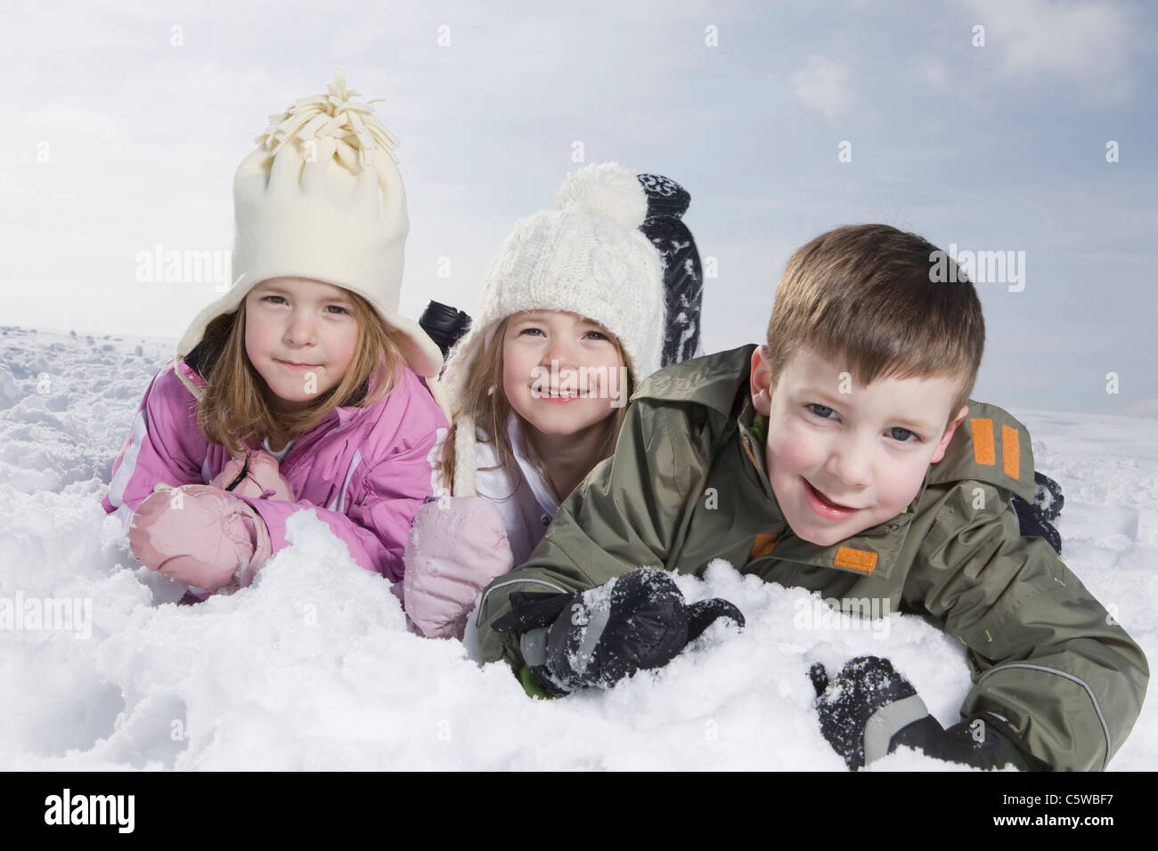 Deutschland, Bayern, München, Kinder (4-5) (8-9) liegen im Schnee, Porträt Stockfoto