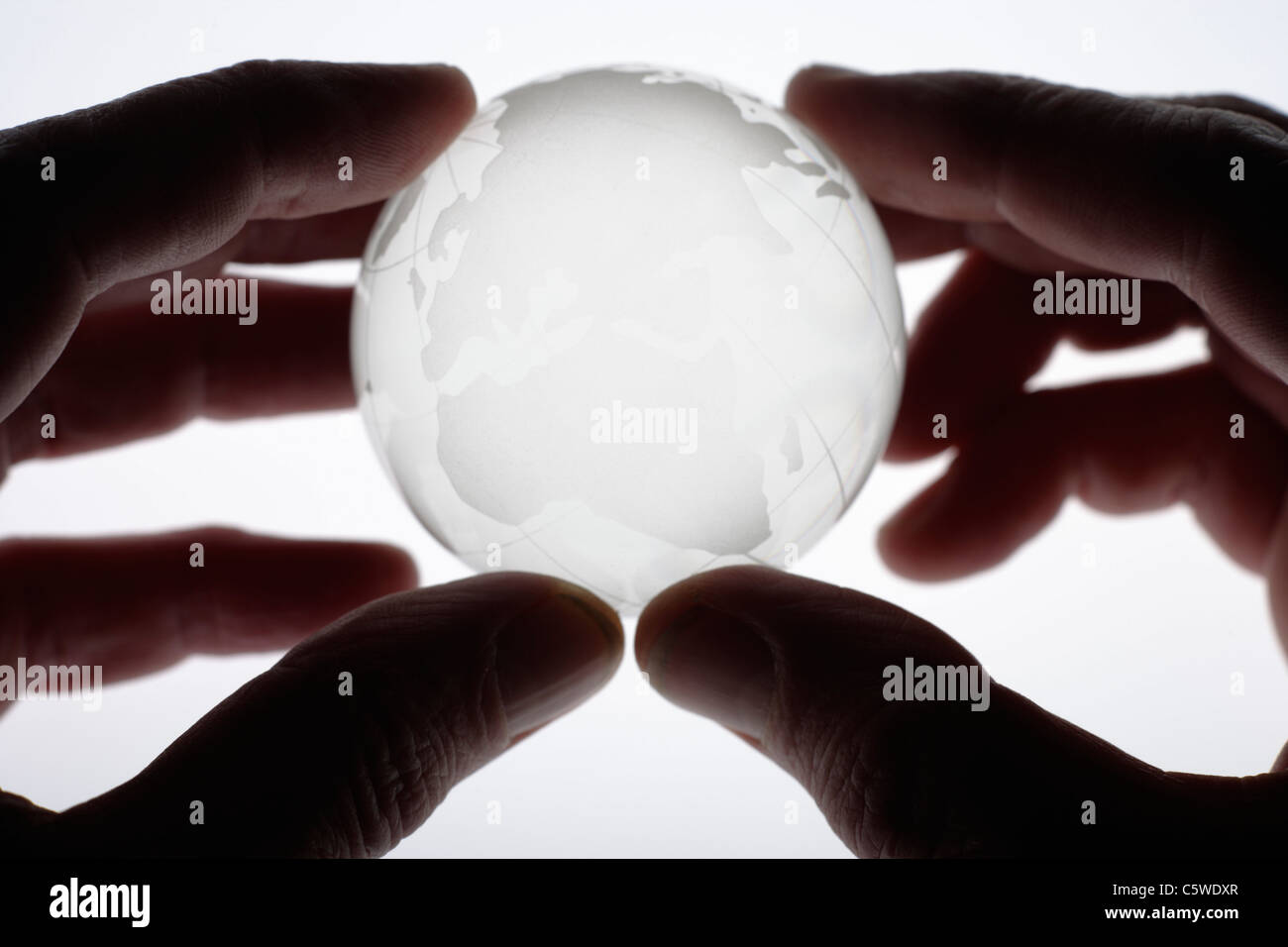 Menschliche Finger halten Glaskugel vor weißem Hintergrund, Nahaufnahme Stockfoto