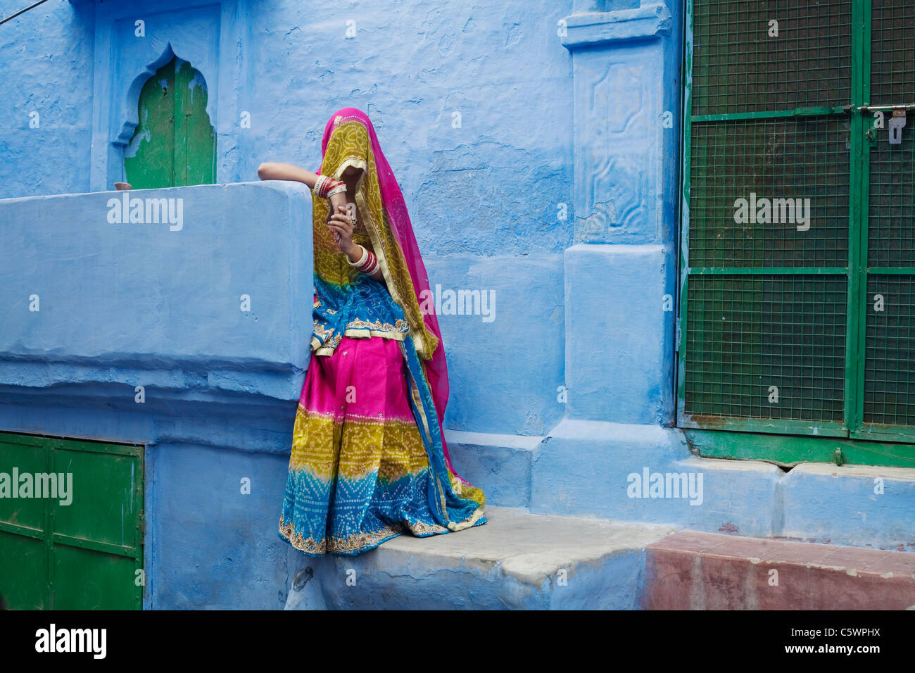 Eine Frau im traditionellen indischen Gewand vor einem der berühmten blau bemalten Häuser von Jodhpur, Indien im Staat Rajasthan Stockfoto