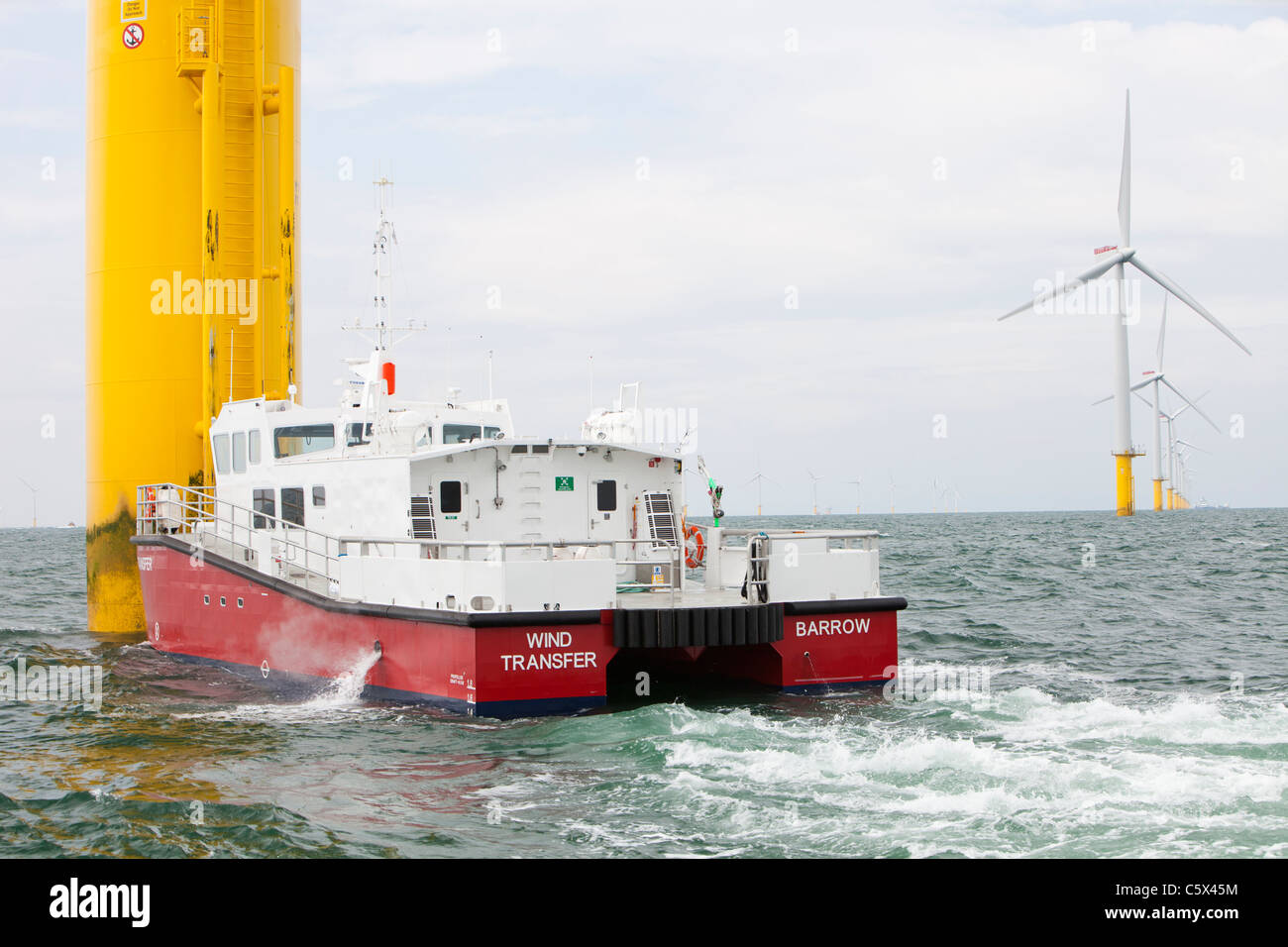 Ein Versorgungsschiff neben einer Windkraftanlage des Projekts Walney Offshore Windpark, aus Barrow in Furness, Cumbria, UK. Stockfoto