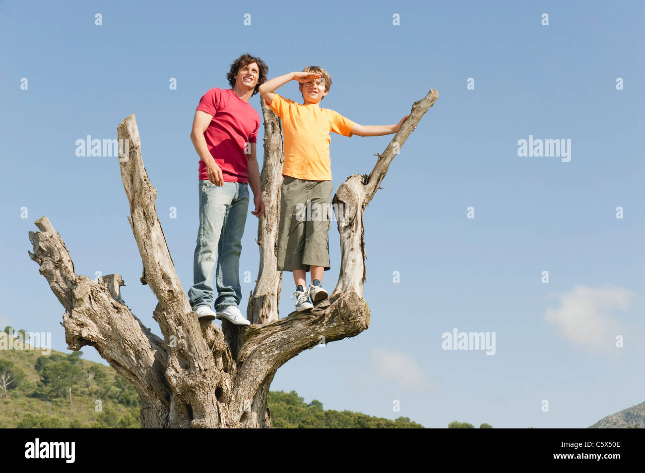 Spanien, Mallorca, Vater und Sohn (8-9) stehend auf Baum Stockfoto