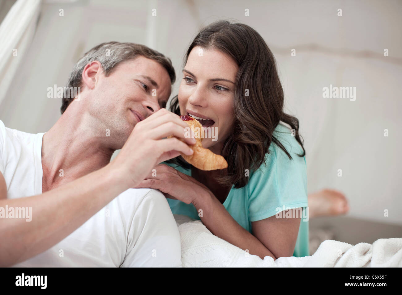 Deutschland, Hamburg, paar im Schlafzimmer, Frau beißen in croissant Stockfoto