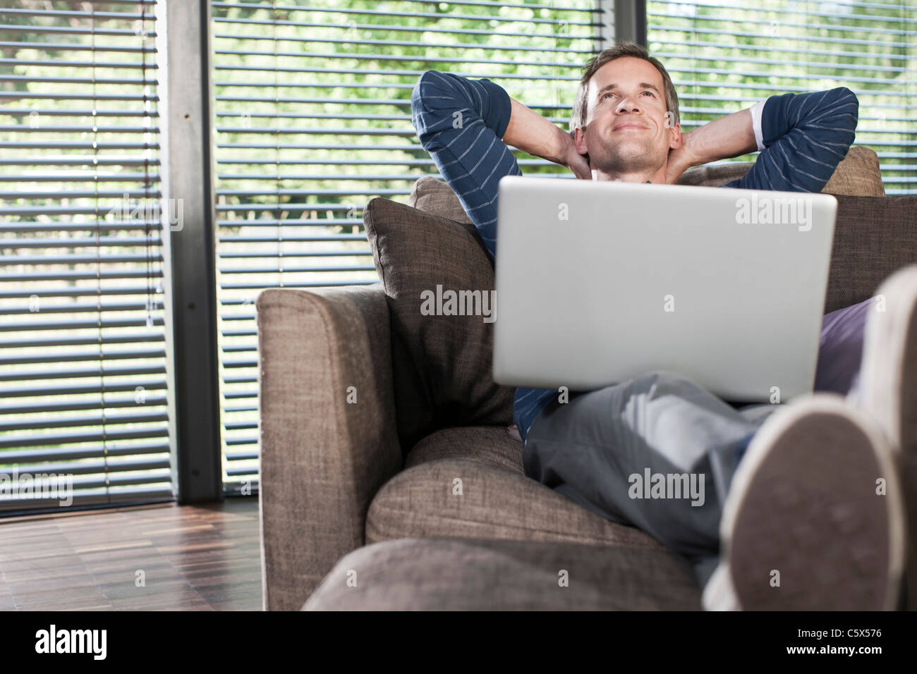 Deutschland, Hamburg, Mann im Wohnzimmer mit laptop Stockfoto