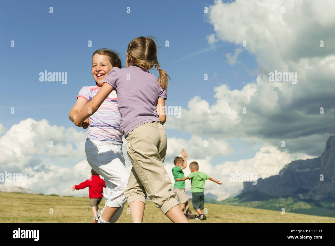 Italien, Seiseralm, Kinder (6-7), (8-9), (4-5) spielen auf Wiese Stockfoto