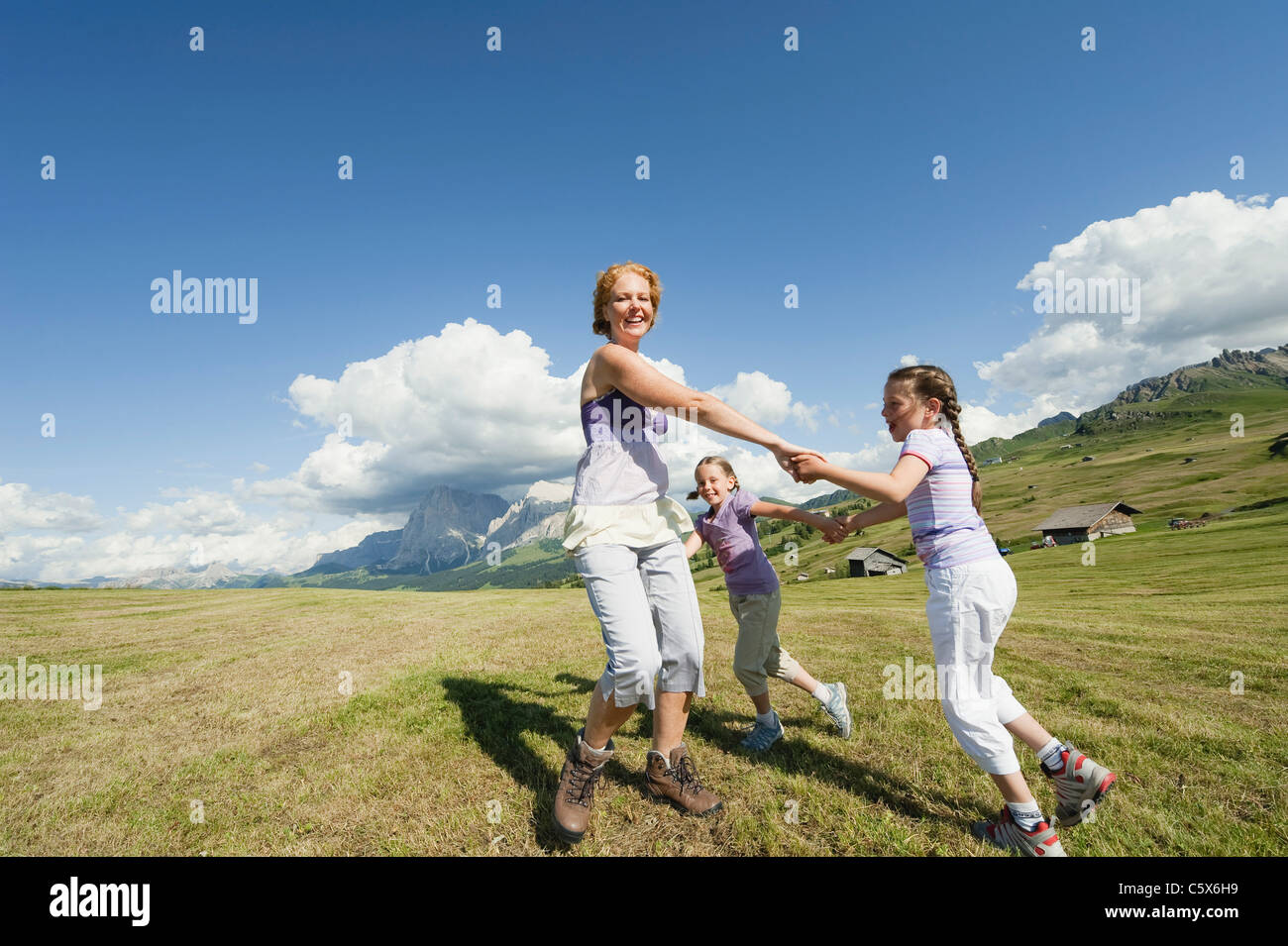 Italien, Seiseralm, Mutter und Kinder (6-7), (8-9) tanzen auf Wiese, lachen, Porträt Stockfoto