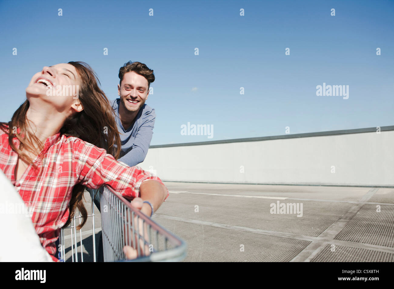 Deutschland, Berlin, junge Mann drängen junge Frau im Warenkorb Stockfoto