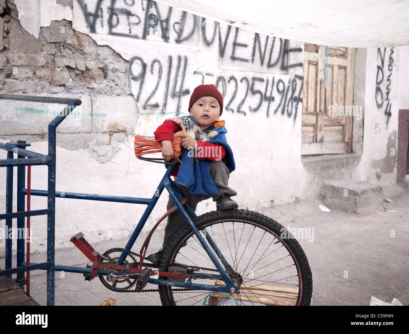 Ein kleiner Junge klettert auf einem Fahrrad in Südamerika. Stockfoto