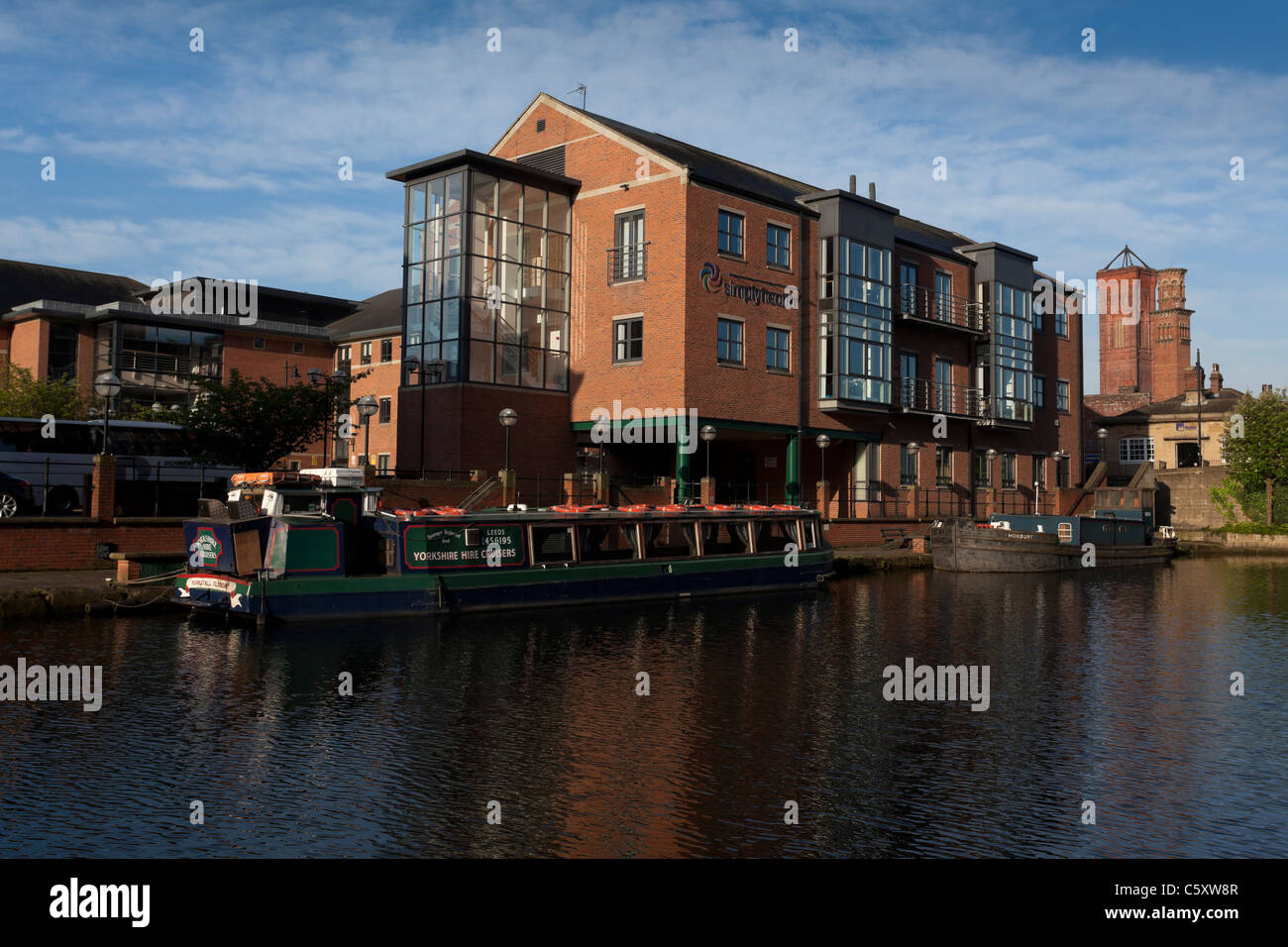 Moderne Gebäude durch den Fluss Aire in Leeds, Teil der Uferpromenade-Sanierung. Stockfoto