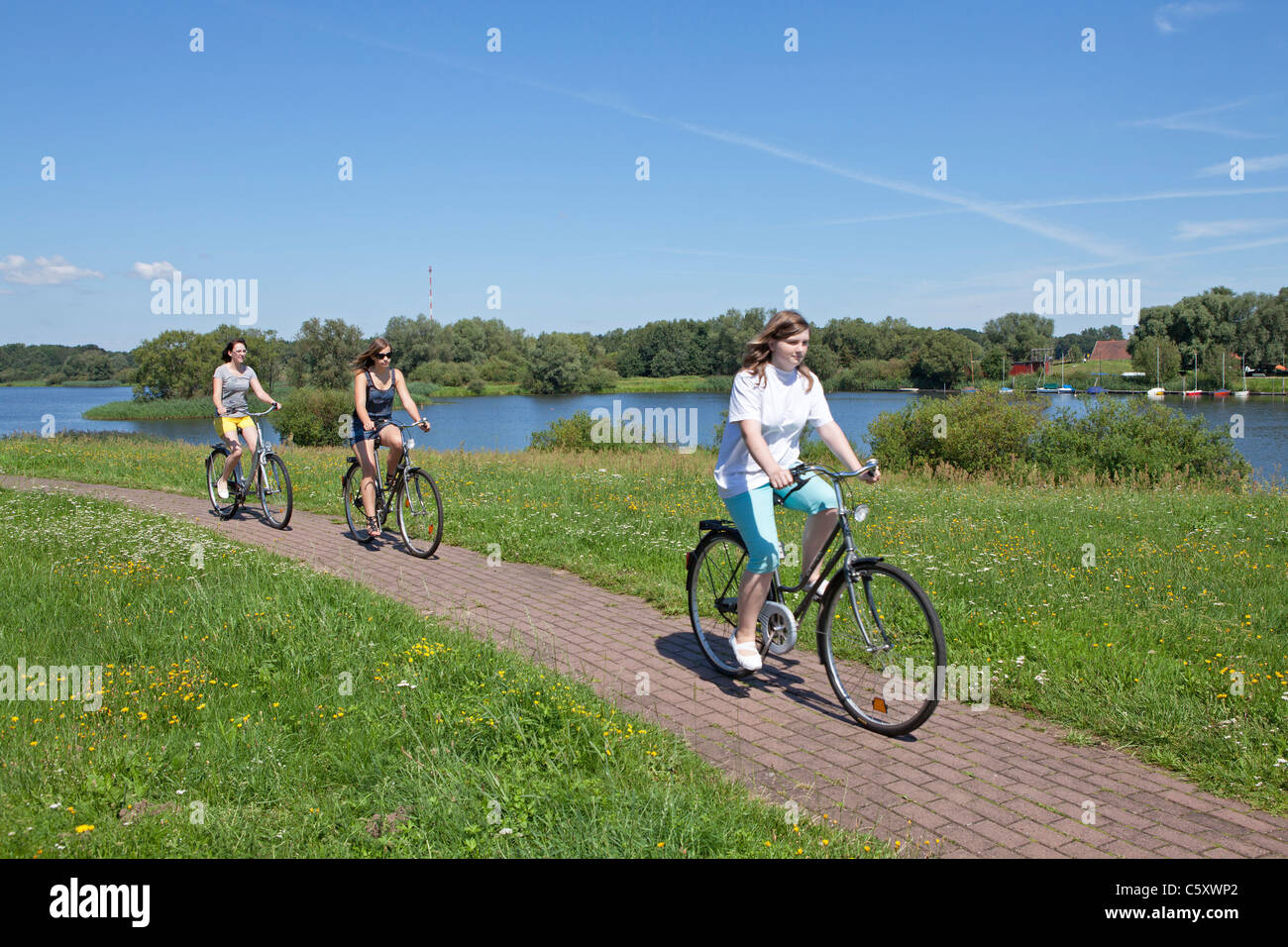 drei Mädchen, Radfahren auf dem Deich neben See Gartow, Nature Reserve Elbufer-Drawehn, Niedersachsen Stockfoto