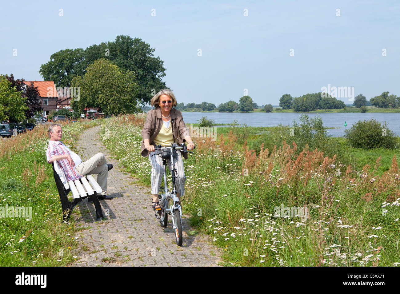 Frau, Radfahren auf dem Deich neben Fluss Elbe in der Nähe von Wussegel in der Nähe von Hitzacker, Nature Reserve Elbufer-Drawehn, Niedersachsen Stockfoto