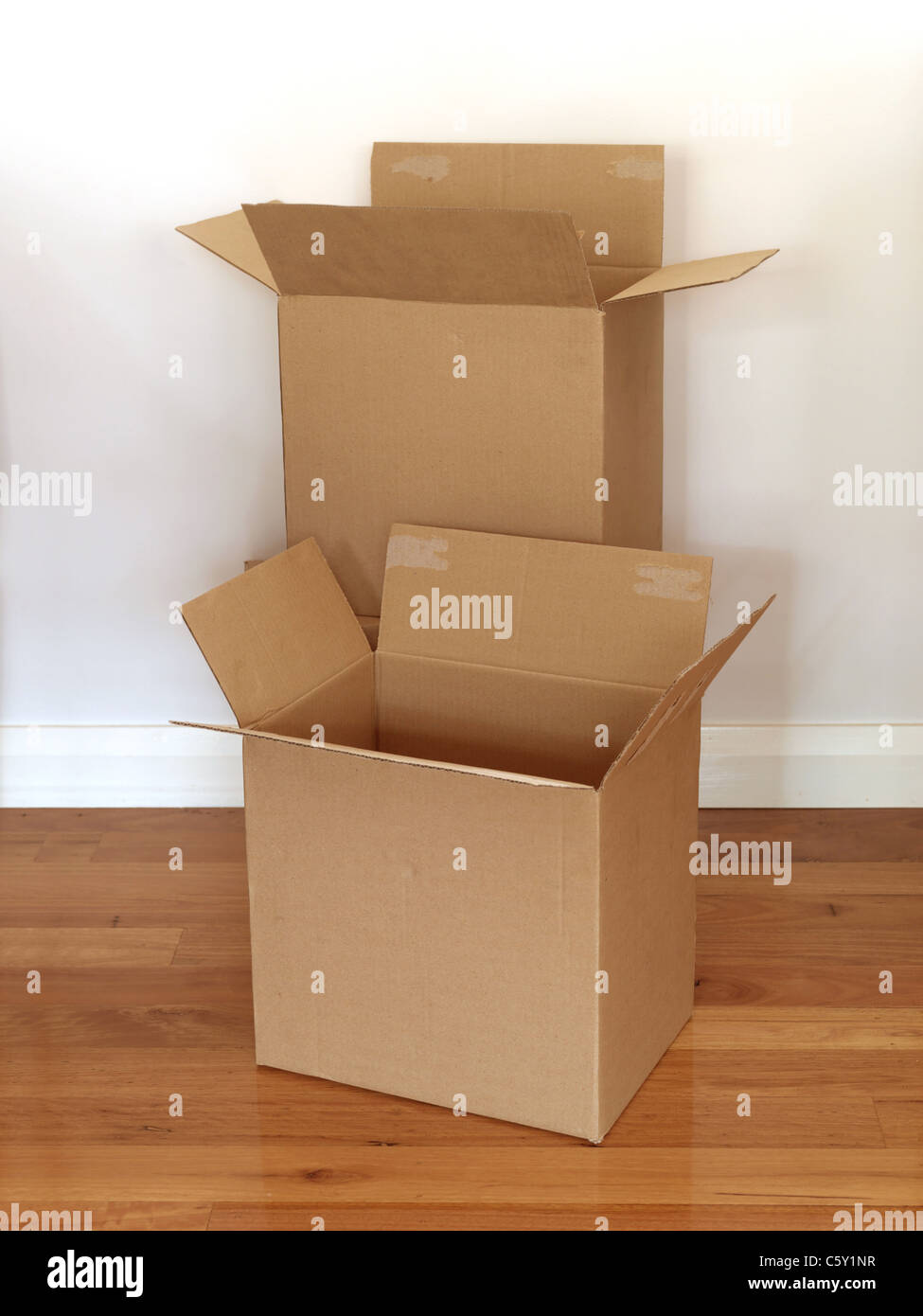 Kartons, die isoliert auf einem Holzfußboden Stockfoto