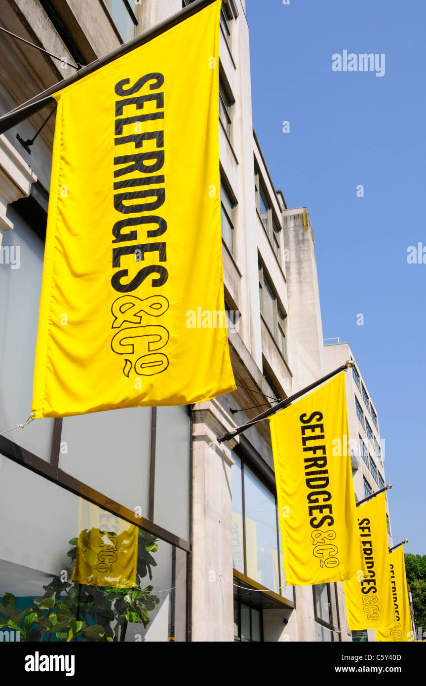 Selfridges & Co Einzelhandelsgeschäft Kaufhaus ikonisches leuchtend gelbes Logo Banner blauer Himmel Sonnentag im West End London England Stockfoto