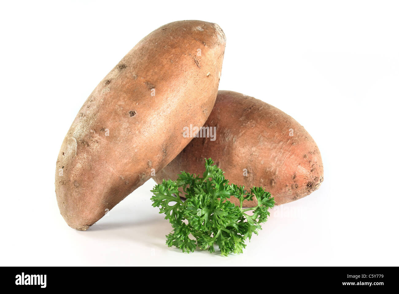 zwei süße Kartoffeln und Petersilie auf weißem Hintergrund Stockfoto