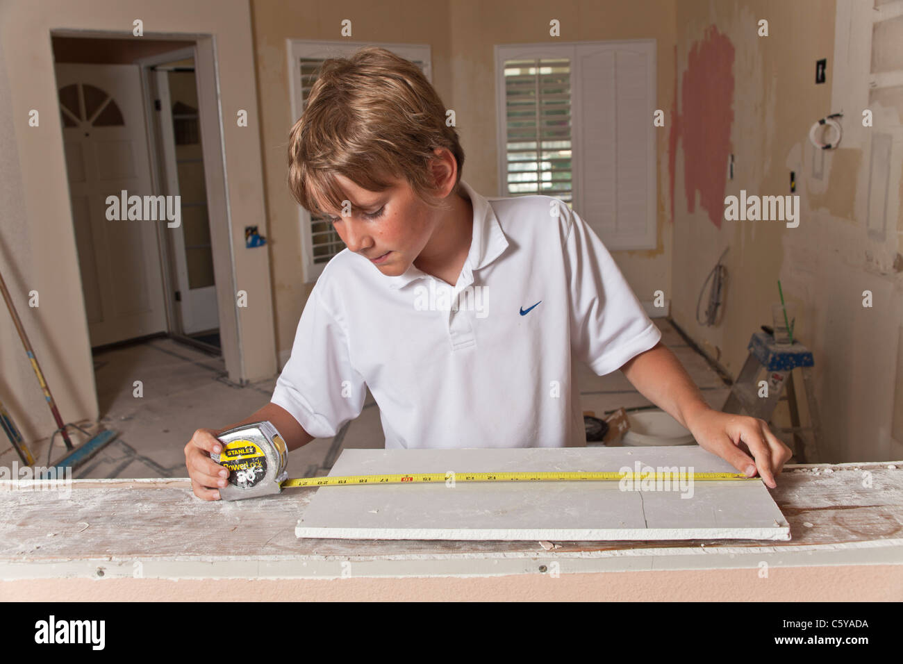 Präzise genau genau genau 11-12 Jahre Jahre alt kaukasischen junge Maßnahmen Wallboard während Küche remodel.son Arbeit erleben Stockfoto