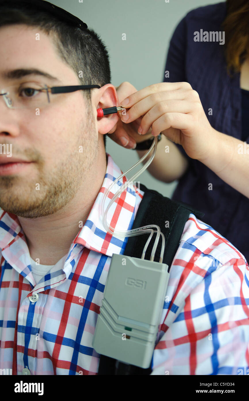 Nahaufnahme von Audiologie und Taubheit männlichen Studenten mit Ohr Hörgerät von Studentin Stockfoto