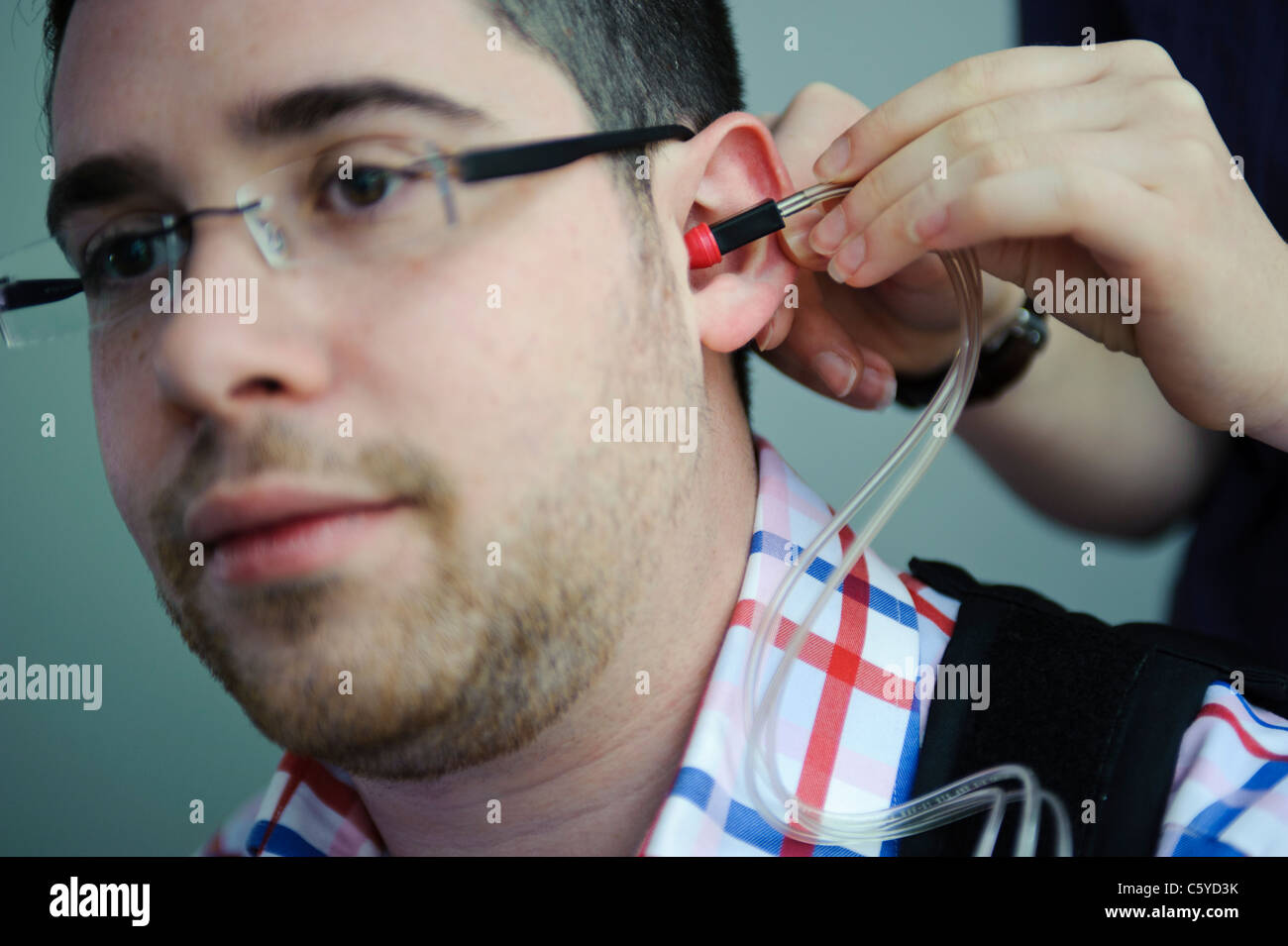 Nahaufnahme von Audiologie und Taubheit männlichen Studenten mit Ohr Hörgerät von Studentin Stockfoto