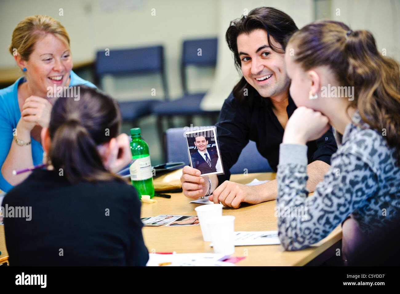 Erwachsenen Lehrer im Klassenzimmer hält ein Foto eines Prominenten in Richtung zwei Schulkinder im Alter von 12 bis 13 Jahre Stockfoto