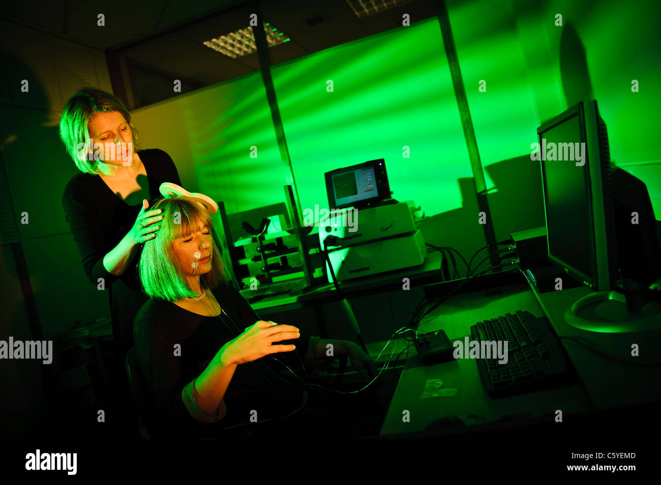 Neurowissenschaftler mit Schlüssel förmigen Paddel Transcranial magnetische Anregung TMS Thema sitzen im Labor Lit grüne durchführen Stockfoto