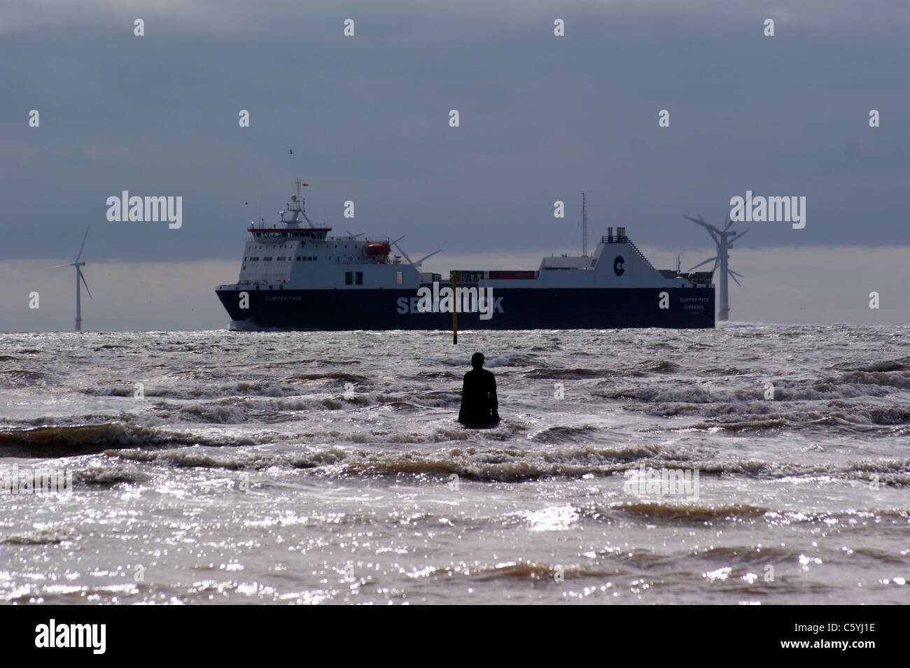 "Woanders", Antony Gormley Statuen auf Crosby Strand, Liverpool, Merseyside, England, Liverpool Windpark, Containerschiff Stockfoto