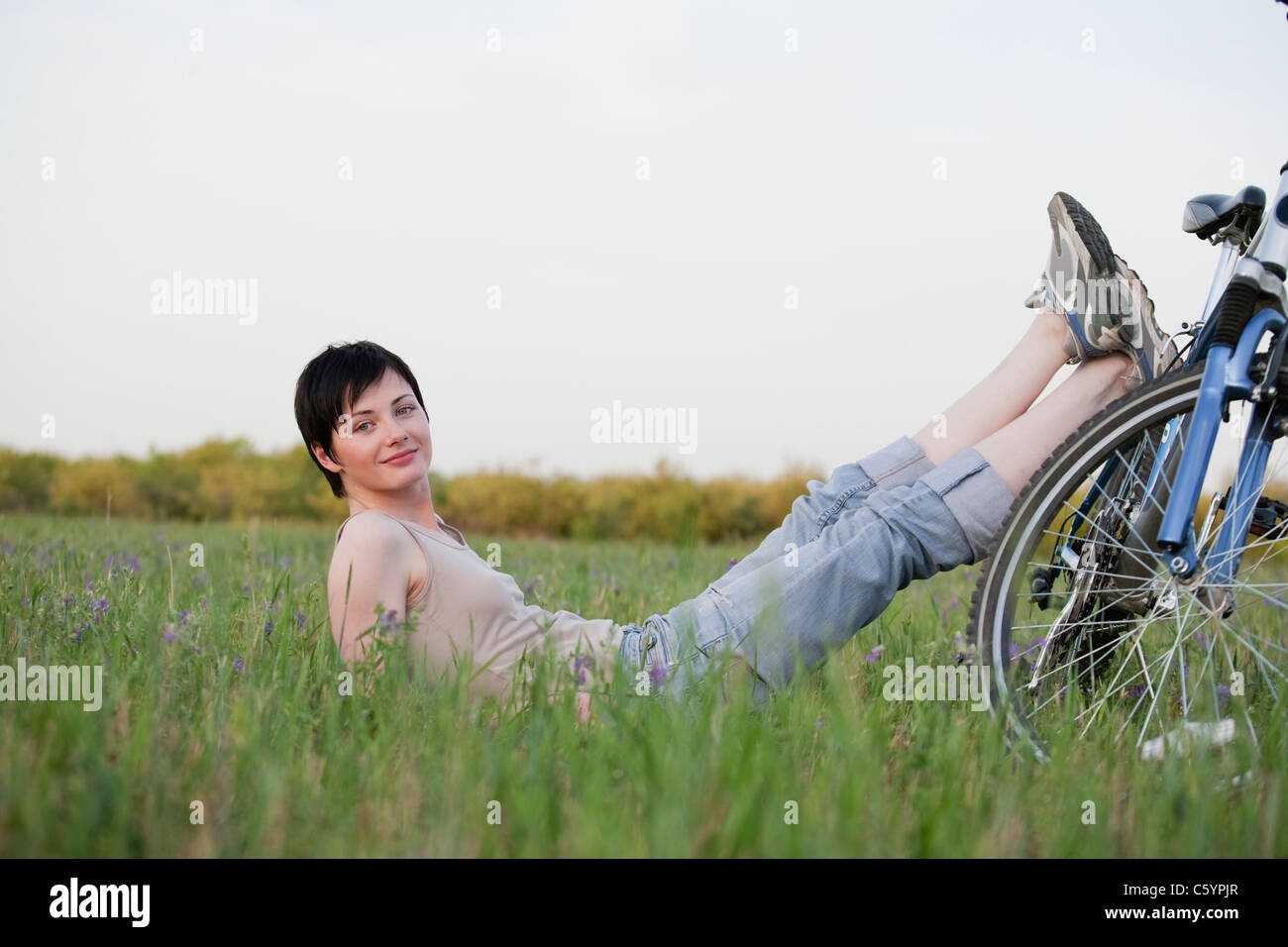 Russland, Voronezh, Frau sitzt in Wiese stützte sich auf Fahrrad Stockfoto