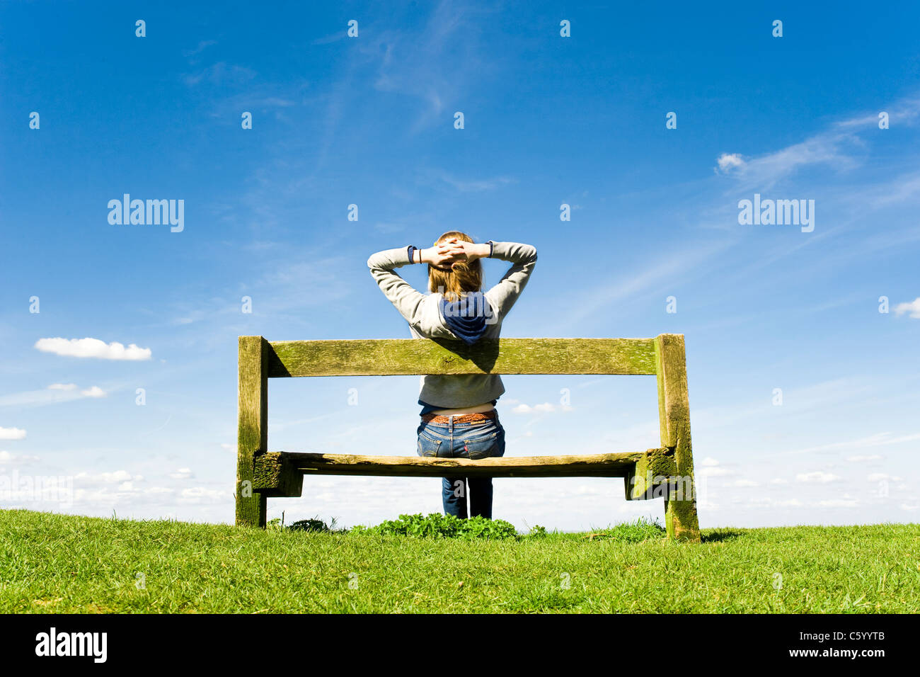 Entspannen Sie sich auf einer Parkbank an einem klaren Sommertag junge Frau Stockfoto