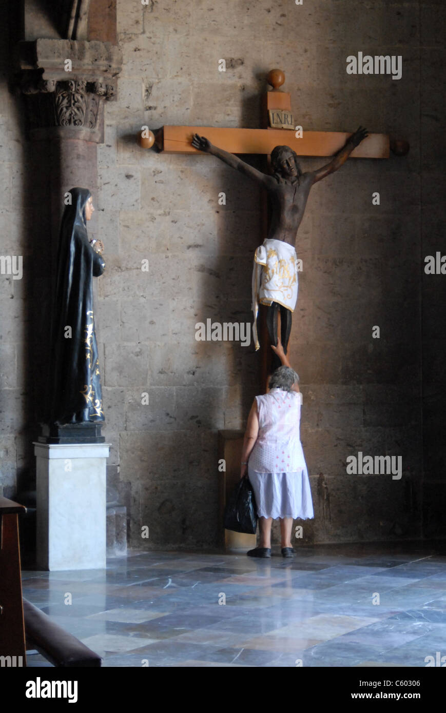 Frau auf schwarzen Christus-Statue beten. Stockfoto