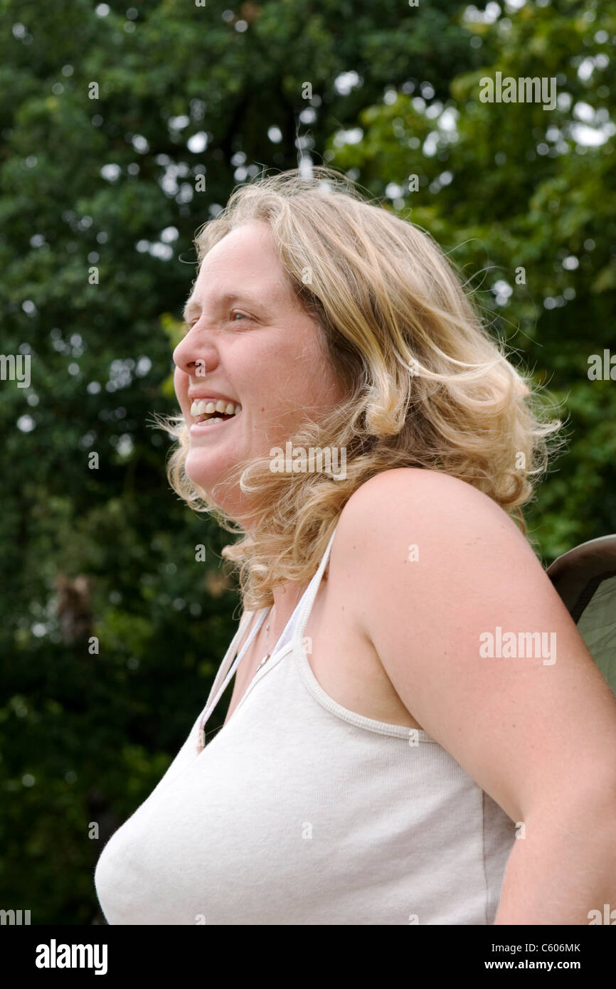 London Hampstead Heath Parliament Hill Porträt einer Blondine lachend Lächeln glücklich weibliche Dame Angler oder Fischer Frau durch Teich Baum Bäume Stockfoto