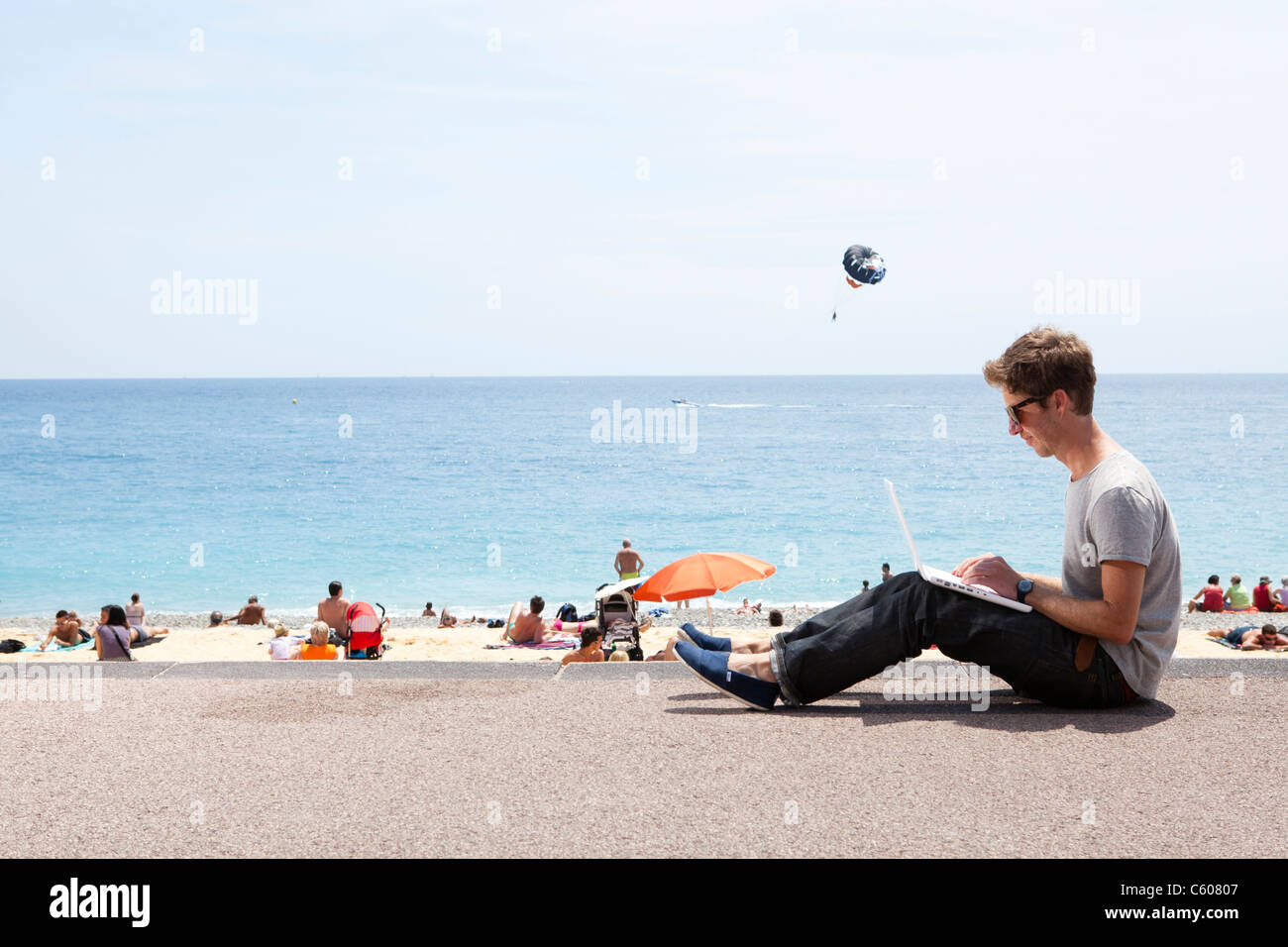 Mann auf Laptop-Computer, Promenade des Anglais, Nizza, Frankreich Stockfoto