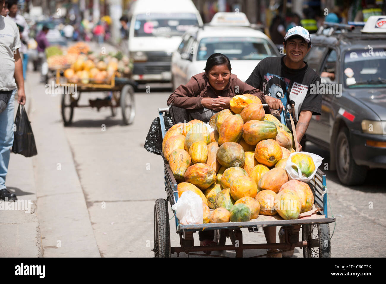 Anbieter drängen einen Wagen voller reife Papaya auf dem Markt in Cajamarca im nördlichen Hochland von Peru. Stockfoto